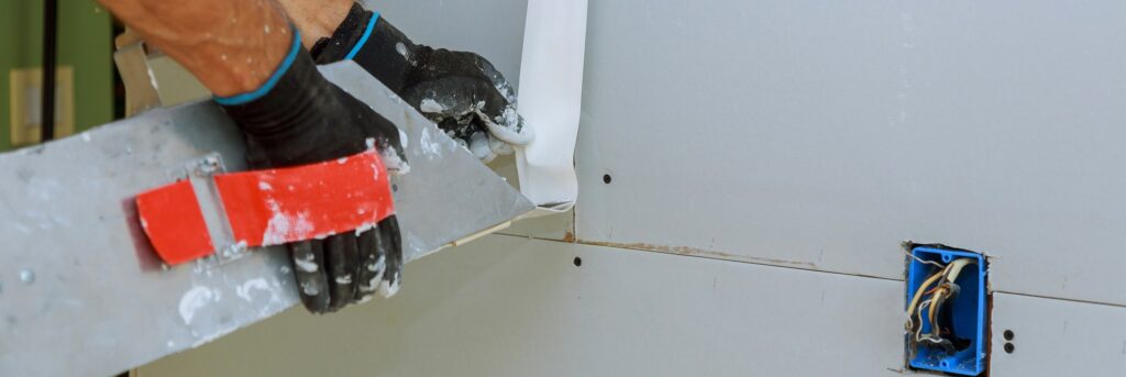 Worker plastering gypsum board wall apartment interior construction